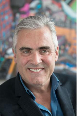 Michael Edward McNamara wearing a suit and tie smiling at the camera