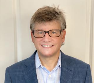 a man wearing glasses and smiling at the camera