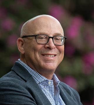 a man wearing glasses and smiling at the camera