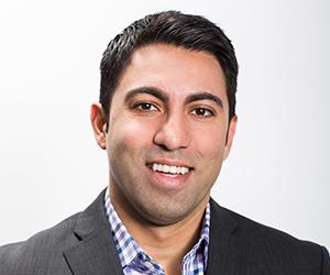 a man wearing a suit and tie smiling at the camera