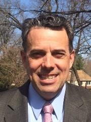 a man wearing a suit and tie smiling at the camera