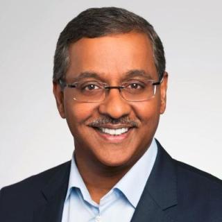 a man wearing a suit and tie smiling at the camera
