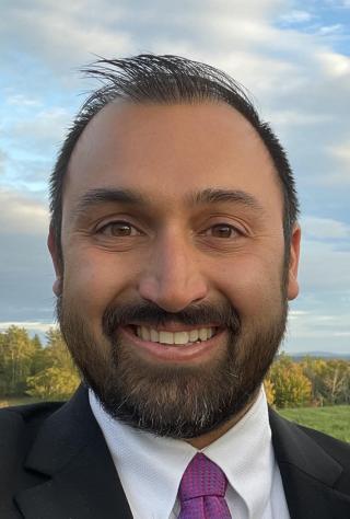 a man wearing a suit and tie smiling at the camera