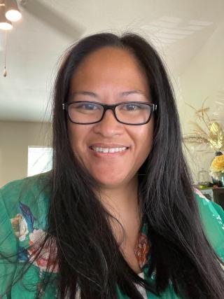 a woman wearing glasses and smiling at the camera