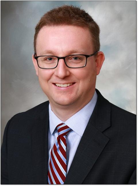 a man wearing a suit and tie smiling at the camera