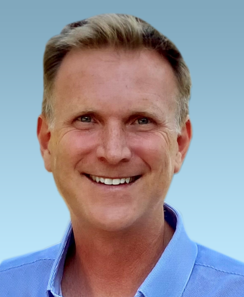 a man wearing a blue shirt and smiling at the camera