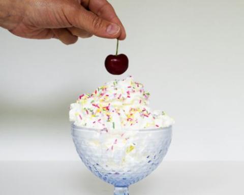 a hand holding a piece of cake on a table