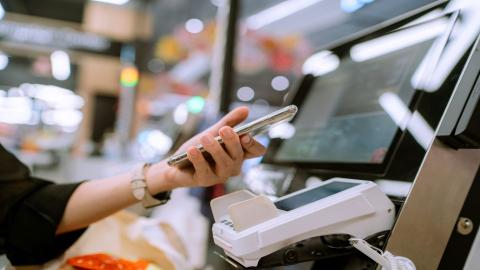 Woman with phone at self checkout