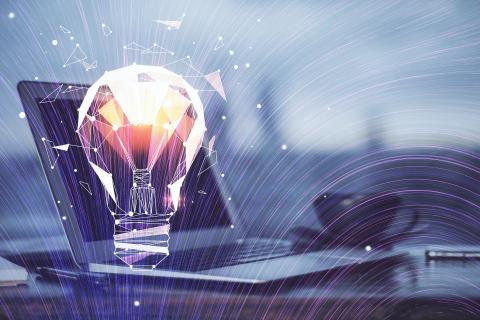 A lightbulb generating new ideas beside a laptop