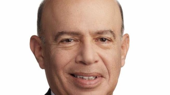 a man wearing a suit and tie smiling at the camera