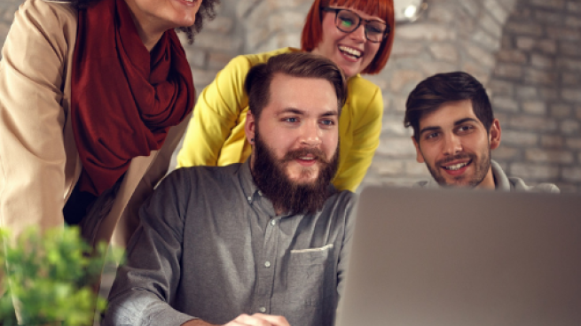 a group of people sitting at a table using a laptop