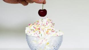 a hand holding a piece of cake on a table